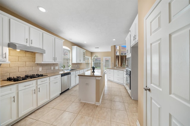 26 Oakmont Ct, Jersey Village, TX 77064 - kitchen featuring appliances with stainless steel finishes, under cabinet range hood, decorative backsplash, light tile patterned flooring, and white cabinets