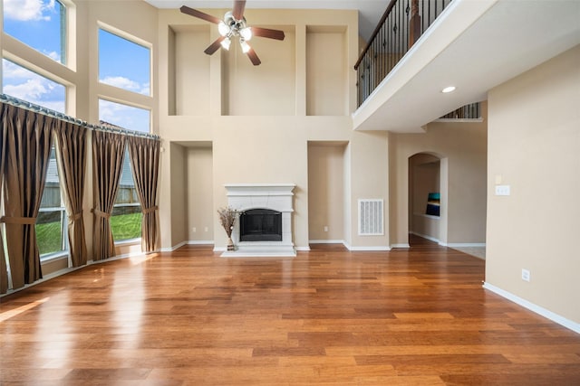 26 Oakmont Ct, Jersey Village, TX 77064 - unfurnished living room featuring a high ceiling, ceiling fan, baseboards, arched walkways, and a fireplace with raised hearth