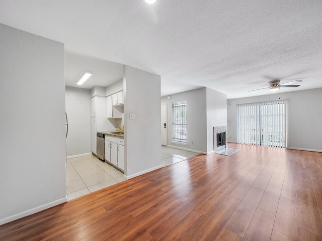 6633 W Airport Blvd Unit 1106, Houston, TX 77035 - unfurnished living room featuring light wood-type flooring, ceiling fan, a fireplace, baseboards, and a sink