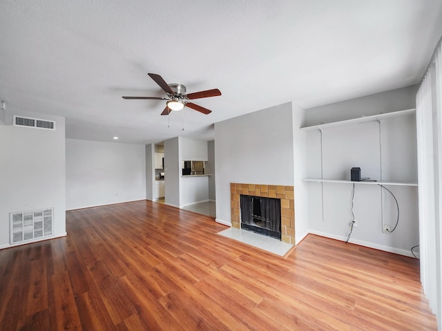 6633 W Airport Blvd Unit 1106, Houston, TX 77035 - unfurnished living room with ceiling fan, wood finished floors, a tile fireplace, and baseboards