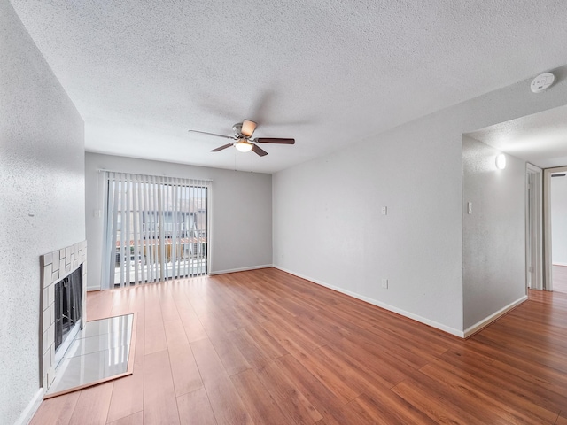 6633 W Airport Blvd Unit 1106, Houston, TX 77035 - unfurnished living room with a ceiling fan, a fireplace, a textured ceiling, wood finished floors, and baseboards
