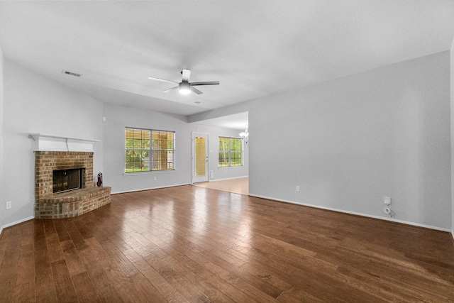 27017 Del Rio Trl W, Magnolia, TX 77355 - unfurnished living room featuring ceiling fan, wood finished floors, a brick fireplace, baseboards, and a chandelier