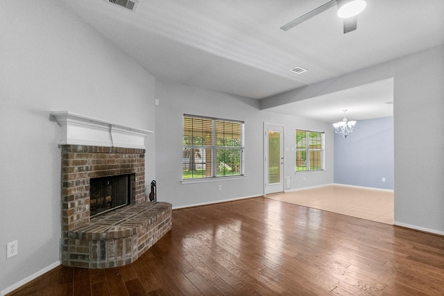 27017 Del Rio Trl W, Magnolia, TX 77355 - unfurnished living room featuring a chandelier, a brick fireplace, ceiling fan, wood finished floors, and baseboards