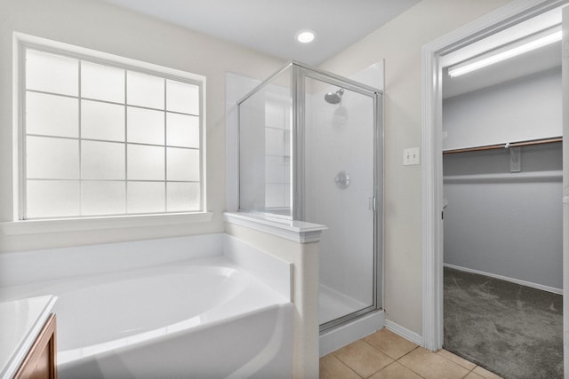 27017 Del Rio Trl W, Magnolia, TX 77355 - bathroom with a walk in closet, a shower stall, a garden tub, and tile patterned flooring