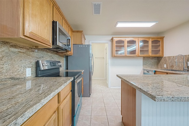 1407 Tiki Dr, Tiki Island, TX 77554 - kitchen featuring stainless steel appliances, a sink, backsplash, glass insert cabinets, and light tile patterned floors