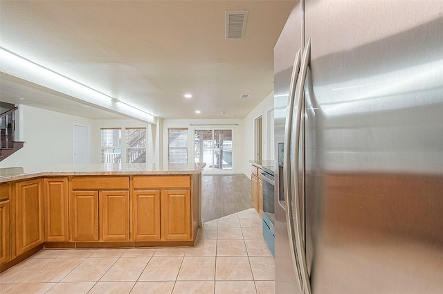 1407 Tiki Dr, Tiki Island, TX 77554 - kitchen with stainless steel appliances, light tile patterned floors, brown cabinetry, and recessed lighting