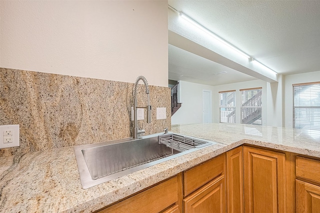 1407 Tiki Dr, Tiki Island, TX 77554 - kitchen featuring a sink, brown cabinetry, and decorative backsplash
