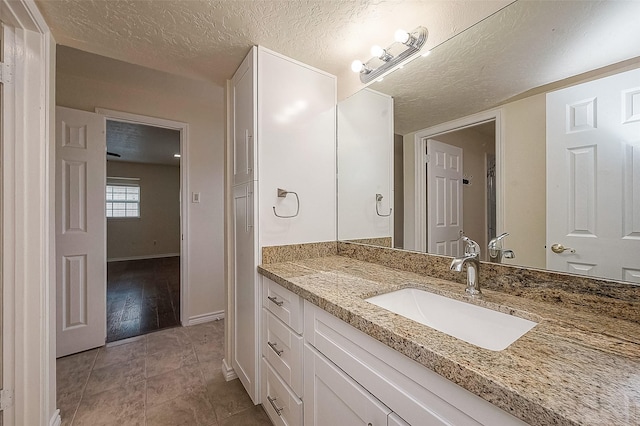 1407 Tiki Dr, Tiki Island, TX 77554 - bathroom featuring vanity, a textured ceiling, baseboards, and tile patterned flooring