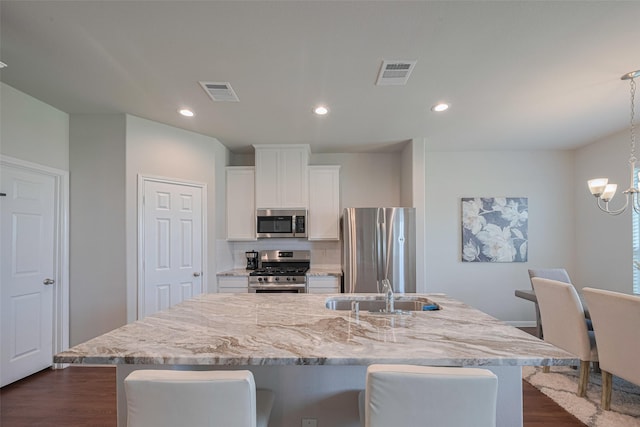 3813 Kirby Ct, Texas City, TX 77591 - kitchen with stainless steel appliances, a center island with sink, dark wood-style floors, white cabinets, and a sink