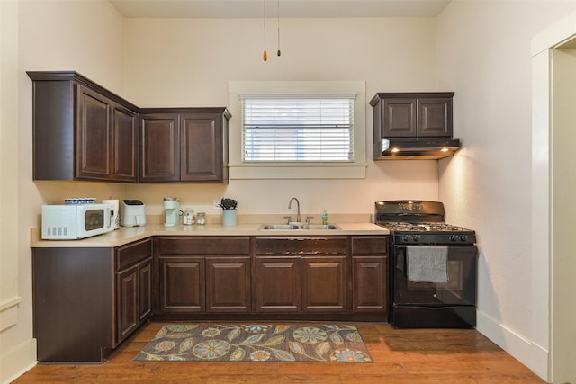 1809 31st St, Galveston, TX 77550 - kitchen featuring a sink, white microwave, black range with gas cooktop, under cabinet range hood, and light countertops