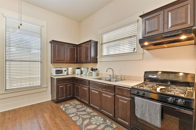 1809 31st St, Galveston, TX 77550 - kitchen with black range with gas cooktop, under cabinet range hood, a sink, white microwave, and light countertops