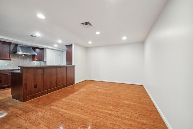 914 Main St Unit 1104, Houston, TX 77002 - kitchen with wall chimney exhaust hood, recessed lighting, backsplash, light wood finished floors, and dark brown cabinets
