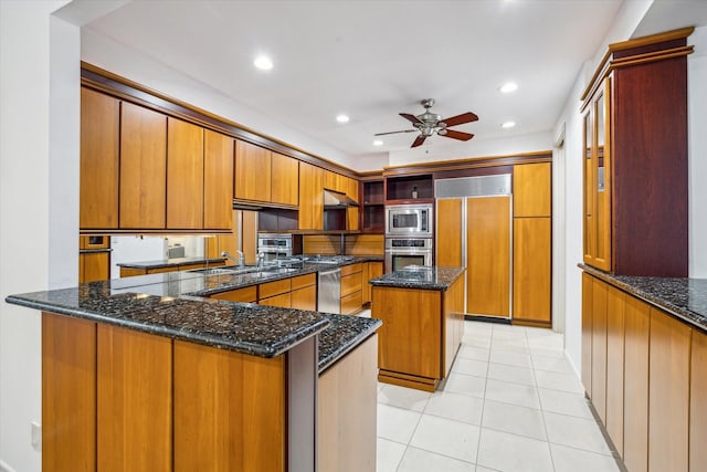 4 River Hollow Ln, Houston, TX 77027 - kitchen with built in appliances, a sink, dark stone countertops, ceiling fan, and brown cabinets