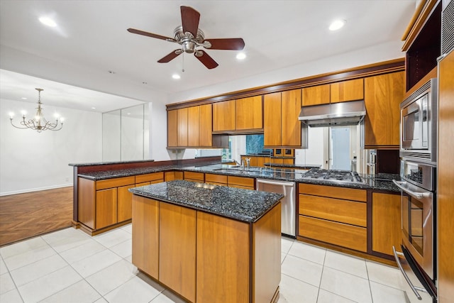 4 River Hollow Ln, Houston, TX 77027 - kitchen featuring a peninsula, brown cabinetry, appliances with stainless steel finishes, a ceiling fan, and under cabinet range hood