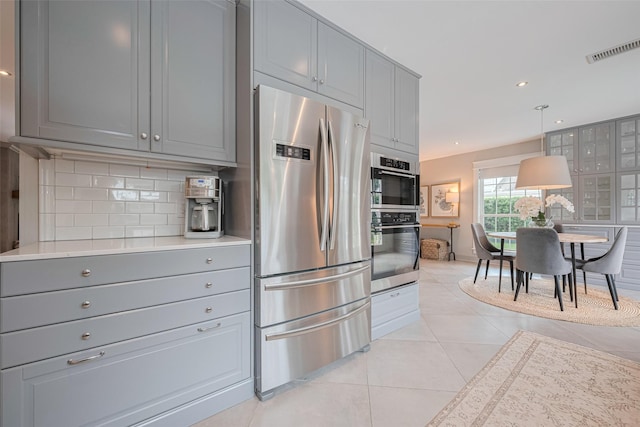 14827 River Forest Dr, Houston, TX 77079 - kitchen with stainless steel appliances, gray cabinetry, decorative backsplash, light tile patterned flooring, and light countertops