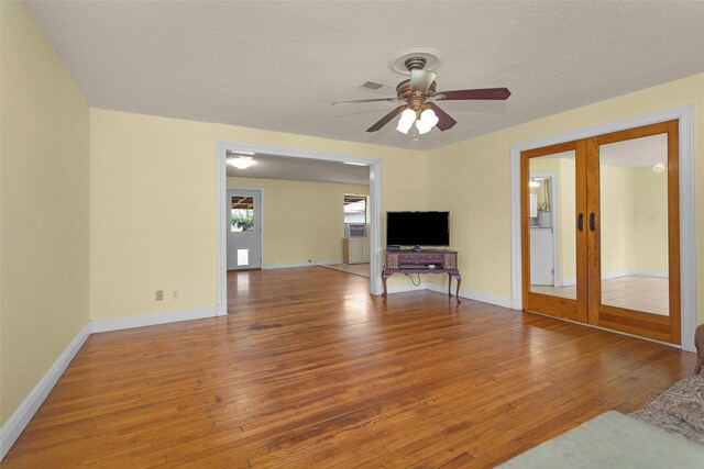 511 Northwood Dr, Conroe, TX 77303 - unfurnished living room featuring light wood-style floors, french doors, ceiling fan, a textured ceiling, and baseboards