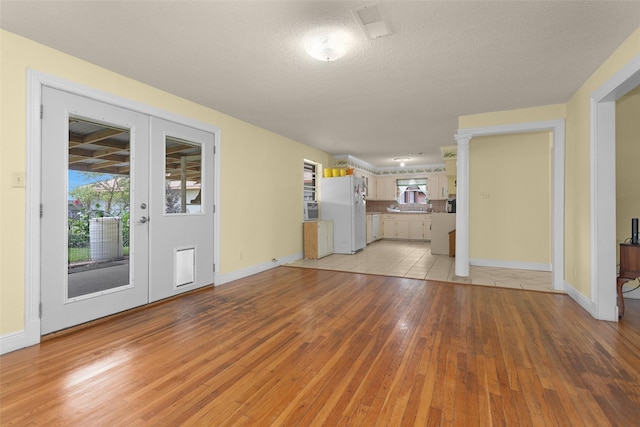 511 Northwood Dr, Conroe, TX 77303 - unfurnished living room featuring light wood finished floors, baseboards, and a textured ceiling