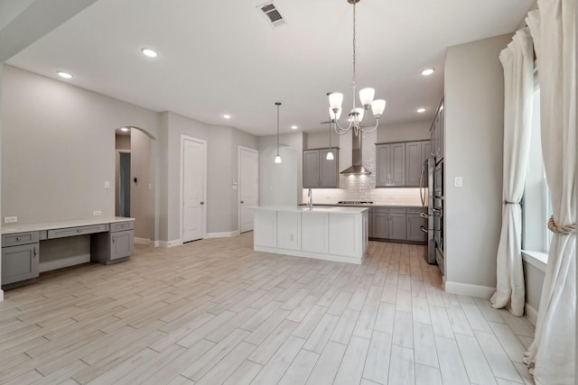 103 Catesby Ct, Conroe, TX 77304 - kitchen featuring gray cabinets, arched walkways, a sink, wall chimney exhaust hood, and decorative backsplash