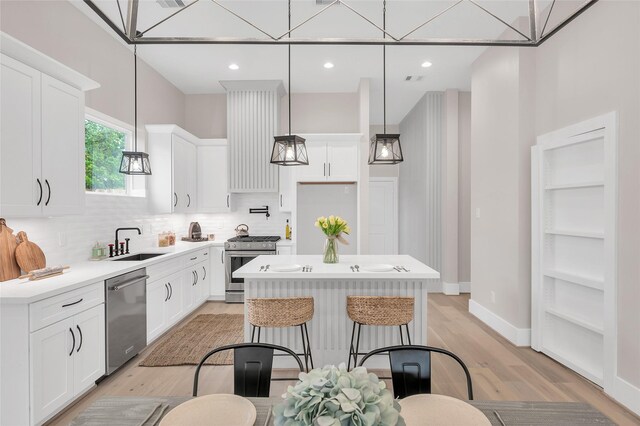 407 Sikes St, Houston, TX 77018 - kitchen with stainless steel appliances, a center island, backsplash, a sink, and light wood-style flooring