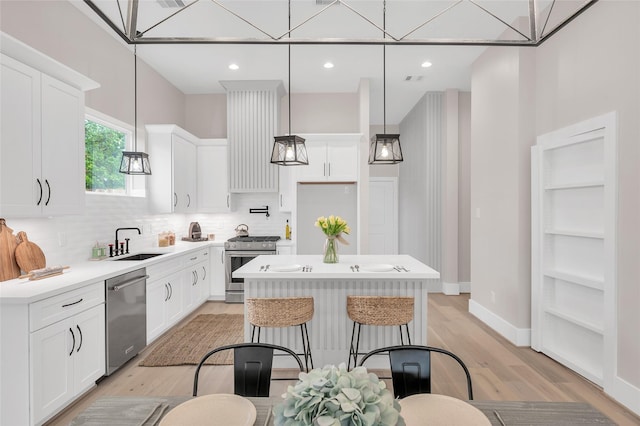 407 Sikes St, Houston, TX 77018 - kitchen featuring stainless steel appliances, a center island, decorative backsplash, light wood-type flooring, and white cabinetry