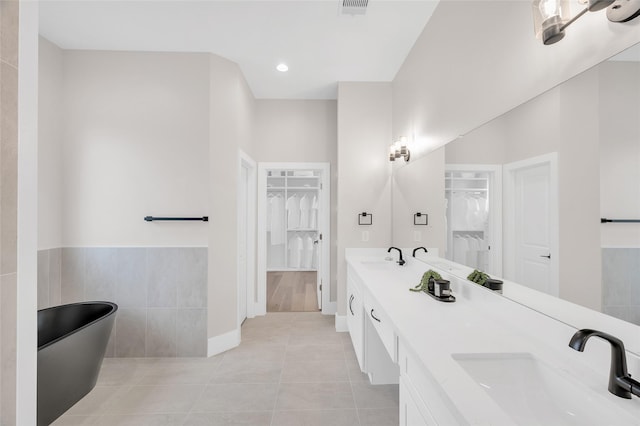 407 Sikes St, Houston, TX 77018 - full bathroom featuring a spacious closet, double vanity, a freestanding bath, tile patterned floors, and tile walls
