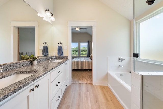 263 Brazos Bnd, Snook, TX 77879 - ensuite bathroom with lofted ceiling, wood finished floors, double vanity, a garden tub, and a ceiling fan