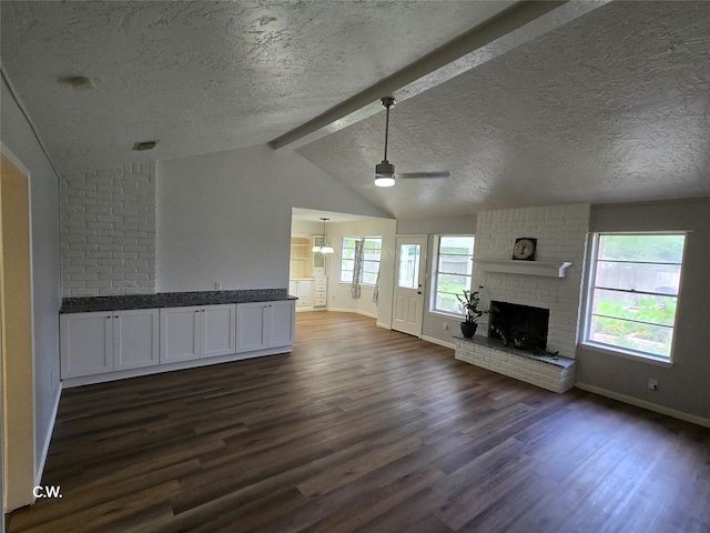 11834 Mulholland Dr, Meadows Place, TX 77477 - unfurnished living room featuring dark wood-type flooring, baseboards, a ceiling fan, a fireplace, and a textured ceiling