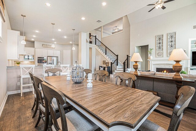 5711 Greenwood Colony Ct, Houston, TX 77059 - dining space featuring ceiling fan, a warm lit fireplace, stairway, recessed lighting, and dark wood-style floors
