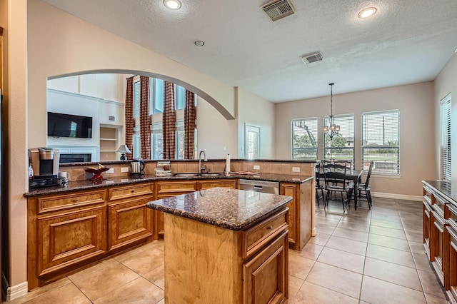 1102 Nautical Ln, Richmond, TX 77469 - kitchen featuring a sink, a center island, brown cabinetry, stainless steel dishwasher, and arched walkways