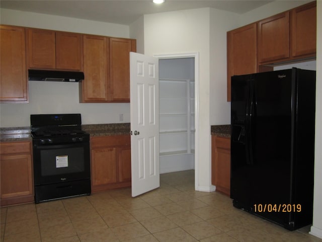 11030 Jacob Crossing Dr, Richmond, TX 77406 - kitchen featuring black appliances, under cabinet range hood, dark countertops, brown cabinets, and light tile patterned floors