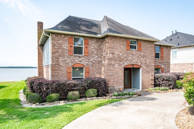 3623 Shore Shadows Dr, Crosby, TX 77532 - view of front facade with a chimney, a water view, brick siding, roof with shingles, and a front yard
