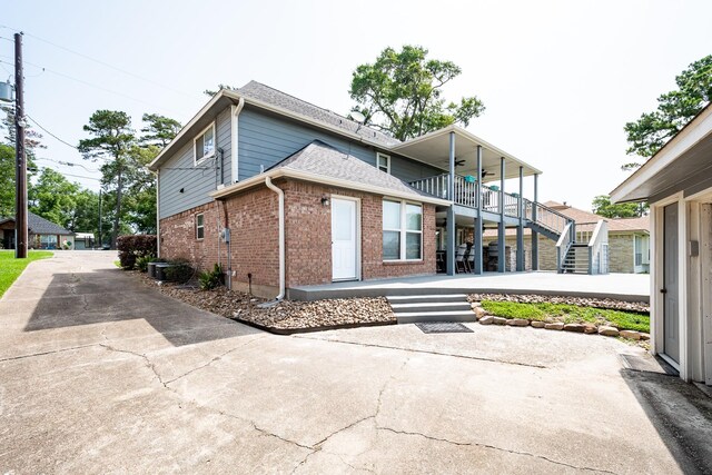 3623 Shore Shadows Dr, Crosby, TX 77532 - back of house featuring stairway, brick siding, a patio, and a shingled roof