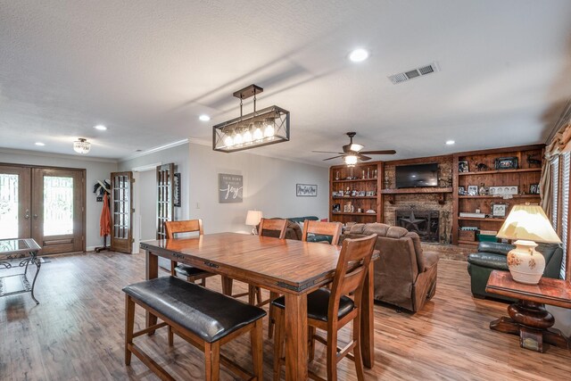 3623 Shore Shadows Dr, Crosby, TX 77532 - dining area with a fireplace, a ceiling fan, crown molding, light wood-style flooring, and recessed lighting