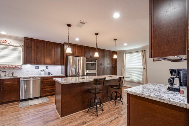 3623 Shore Shadows Dr, Crosby, TX 77532 - kitchen with appliances with stainless steel finishes, light wood-style flooring, a breakfast bar area, a sink, and a kitchen island