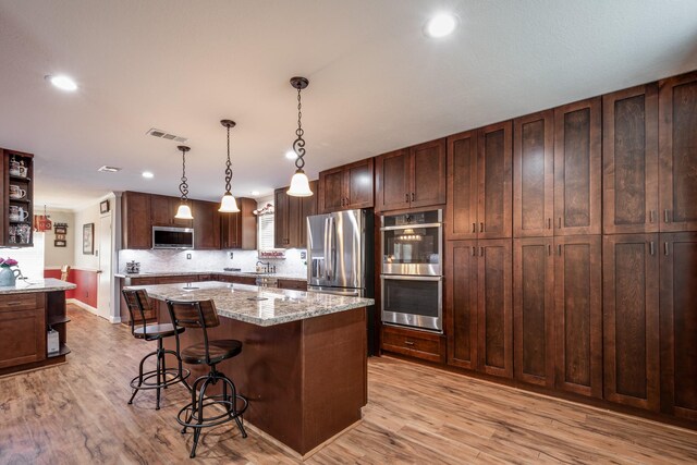 3623 Shore Shadows Dr, Crosby, TX 77532 - kitchen featuring stainless steel appliances, a kitchen breakfast bar, a center island, light wood-style flooring, and recessed lighting