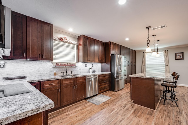 3623 Shore Shadows Dr, Crosby, TX 77532 - kitchen with stainless steel appliances, ornamental molding, a breakfast bar, tasteful backsplash, and light wood finished floors