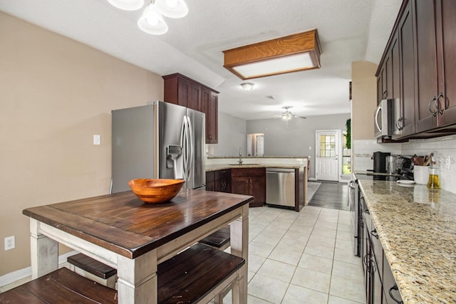 19198 County Road 669e, Alvin, TX 77511 - kitchen with stainless steel appliances, a sink, ceiling fan, tasteful backsplash, and light stone counters