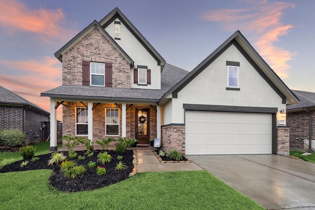 17218 Roxburgh Lake Ln, Hockley, TX 77447 - view of front of house with brick siding, stucco siding, concrete driveway, covered porch, and a front yard