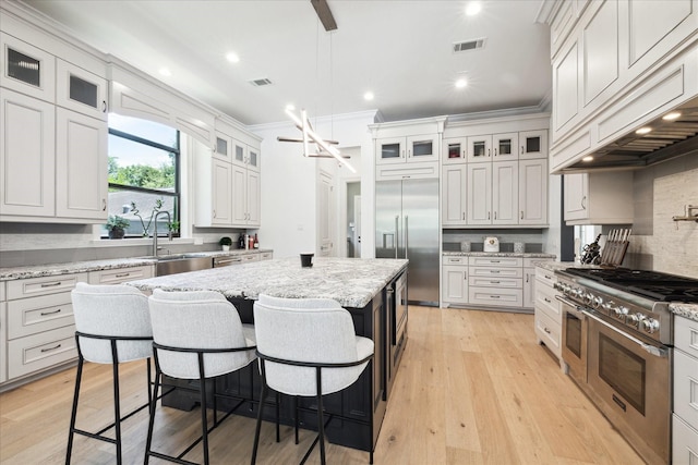 5202 Carew St, Houston, TX 77096 - kitchen with premium appliances, a sink, crown molding, a kitchen island, and a breakfast bar area