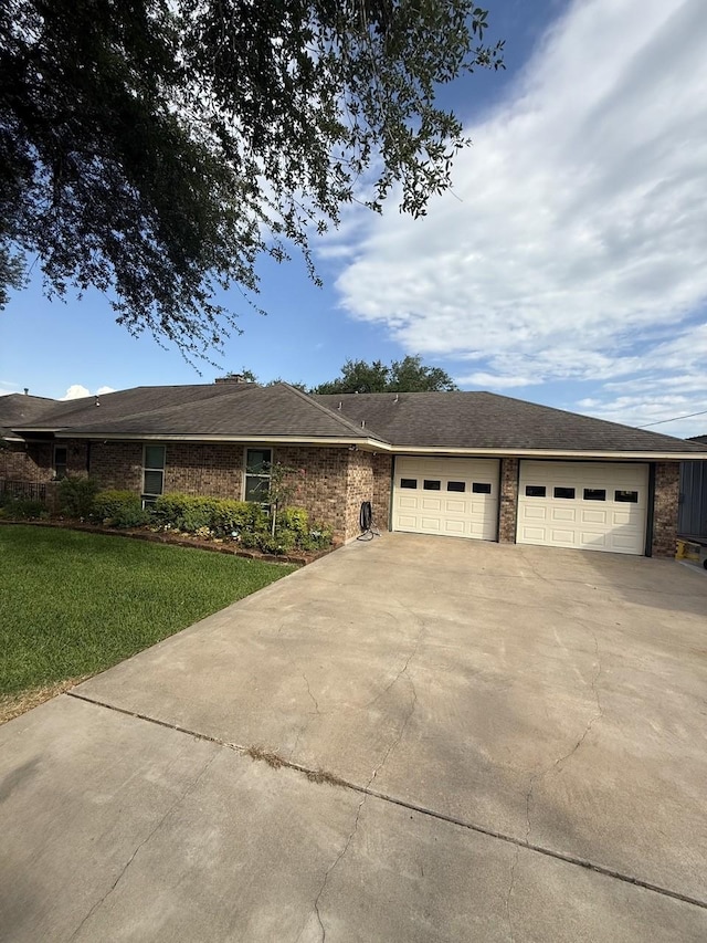 563 12th St, Bay City, TX 77414 - ranch-style house with driveway, a front yard, an attached garage, and brick siding
