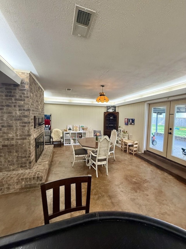 563 12th St, Bay City, TX 77414 - dining space with finished concrete flooring, a fireplace, a textured ceiling, and french doors