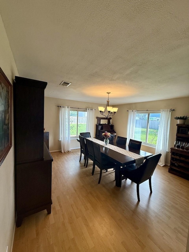 563 12th St, Bay City, TX 77414 - dining area featuring a chandelier, light wood-style floors, a textured ceiling, and baseboards