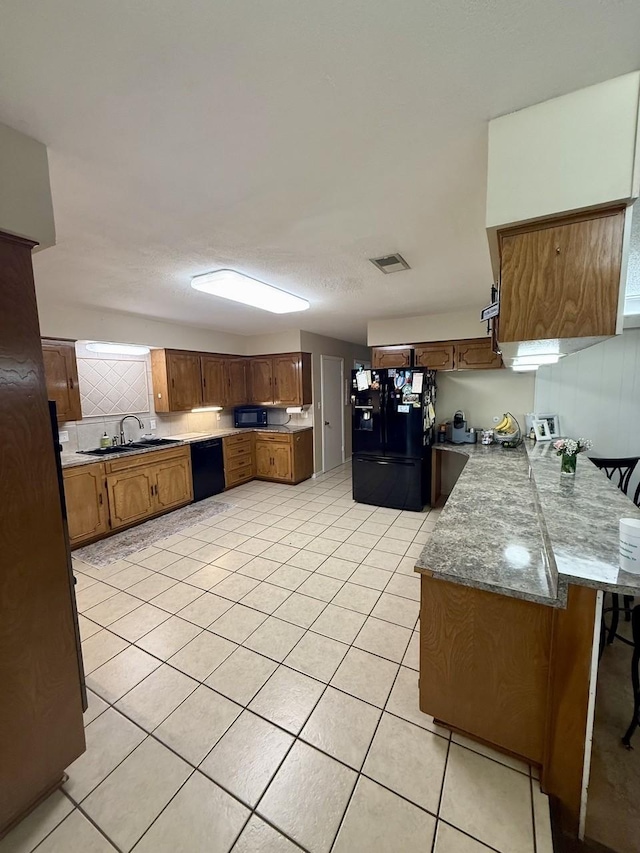 563 12th St, Bay City, TX 77414 - kitchen featuring black appliances, a sink, light tile patterned floors, and a peninsula