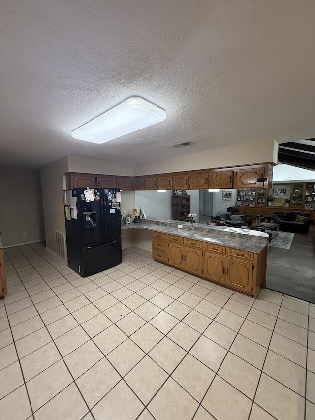 563 12th St, Bay City, TX 77414 - kitchen featuring black fridge with ice dispenser, a textured ceiling, light tile patterned flooring, and brown cabinetry