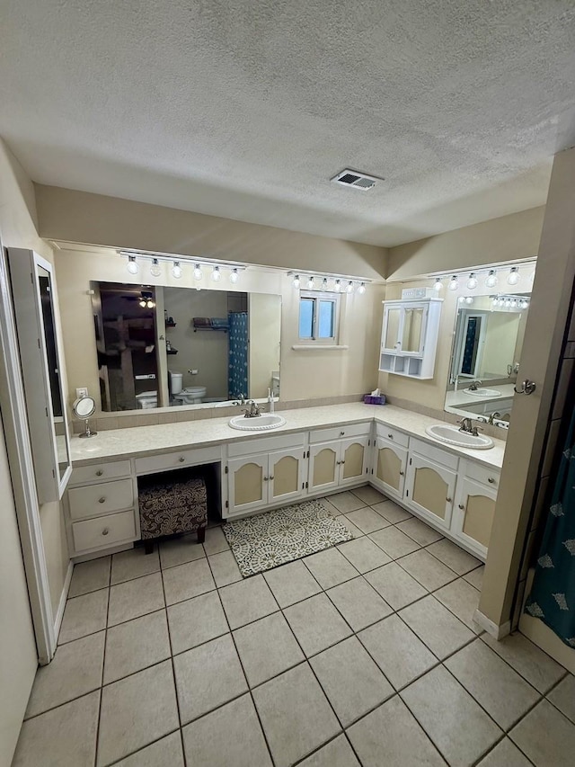 563 12th St, Bay City, TX 77414 - full bathroom with double vanity, tile patterned flooring, toilet, and a textured ceiling