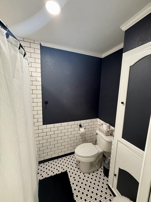 563 12th St, Bay City, TX 77414 - bathroom featuring toilet, ornamental molding, a tile shower, wainscoting, and tile patterned floors