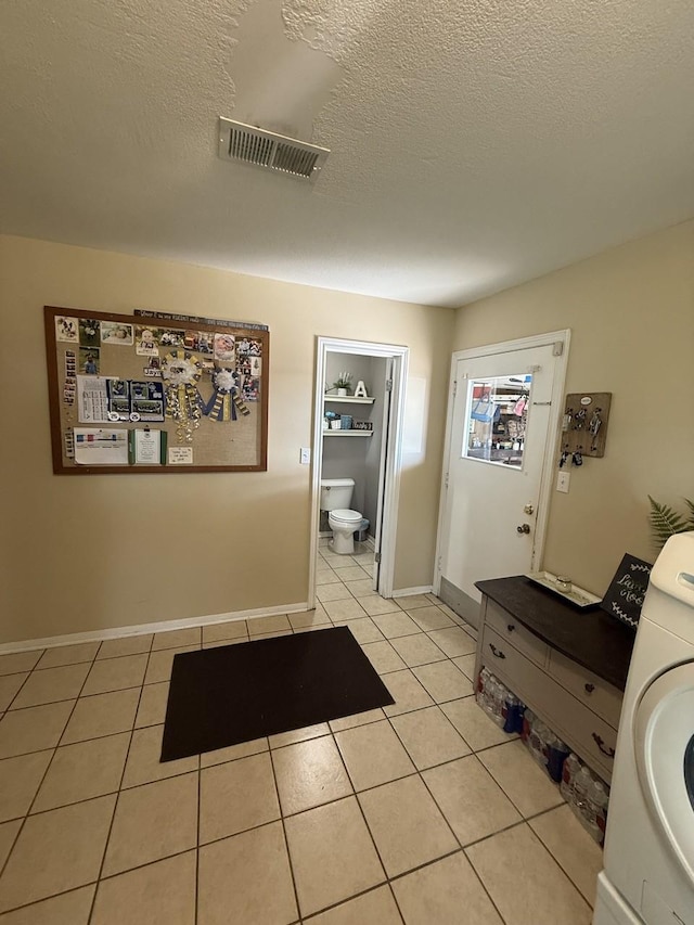 563 12th St, Bay City, TX 77414 - hallway featuring washer / clothes dryer, light tile patterned floors, a textured ceiling, and baseboards