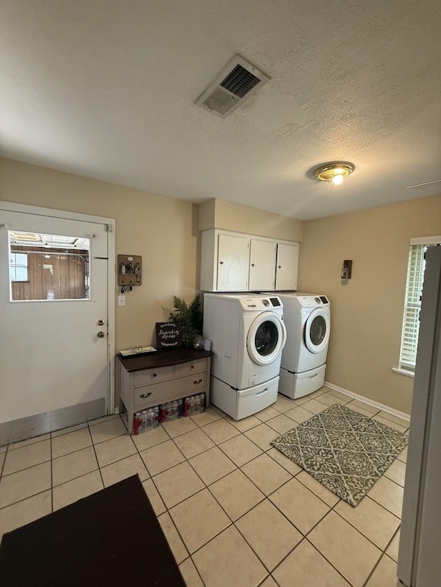 563 12th St, Bay City, TX 77414 - laundry area featuring independent washer and dryer, plenty of natural light, light tile patterned flooring, cabinet space, and a textured ceiling