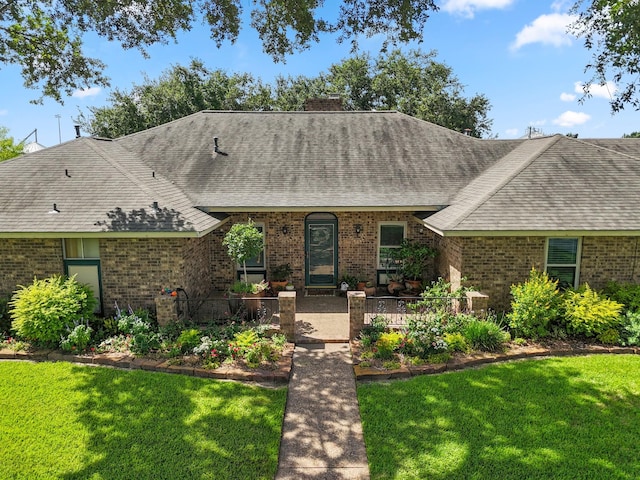 563 12th St, Bay City, TX 77414 - view of front of home featuring roof with shingles, brick siding, a front lawn, and a chimney