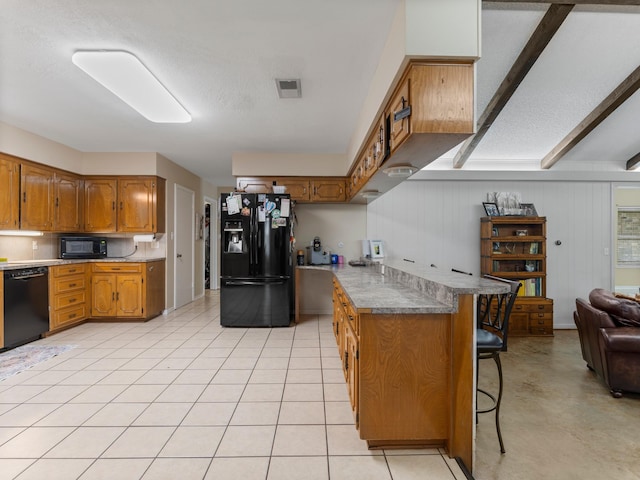 563 12th St, Bay City, TX 77414 - kitchen with black appliances, brown cabinets, a kitchen bar, open floor plan, and a textured ceiling